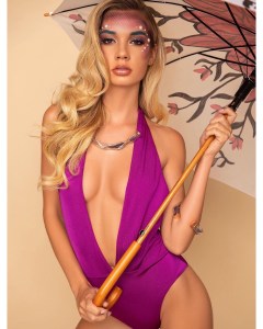Model in purple swimsuit holding parasol and wearing a necklace and bangle